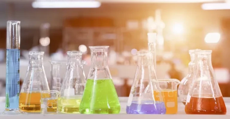 تحقیقات آزمایشگاهی - ظروف شیشهای علمی برای مواد شیمیایی، پسزمینه برای آزمایشها در آزمایشگاه شیمی در فضای داخلی کلاس درس علوم.