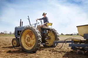 مرد جوان نشسته روی تراکتور در مزرعه