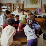 دانش‌آموزان و معلمشان در حال تماشای یک پروژه علمی مدرسه آتشفشان هستند.