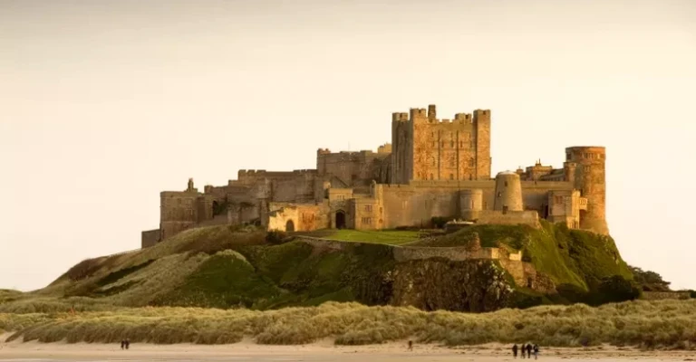 قلعه بامبورگ در طول روز با مردمی که در ساحل قدم می‌زنند