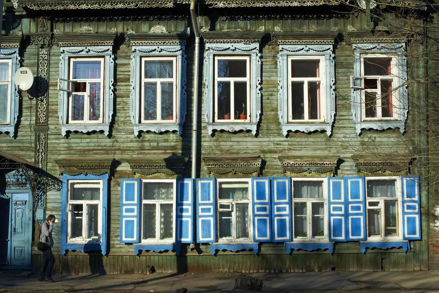 خانه چوبی دو طبقه با تزیینات چوبی پنجره های پر زرق و برق و کرکره های آبی رنگارنگ