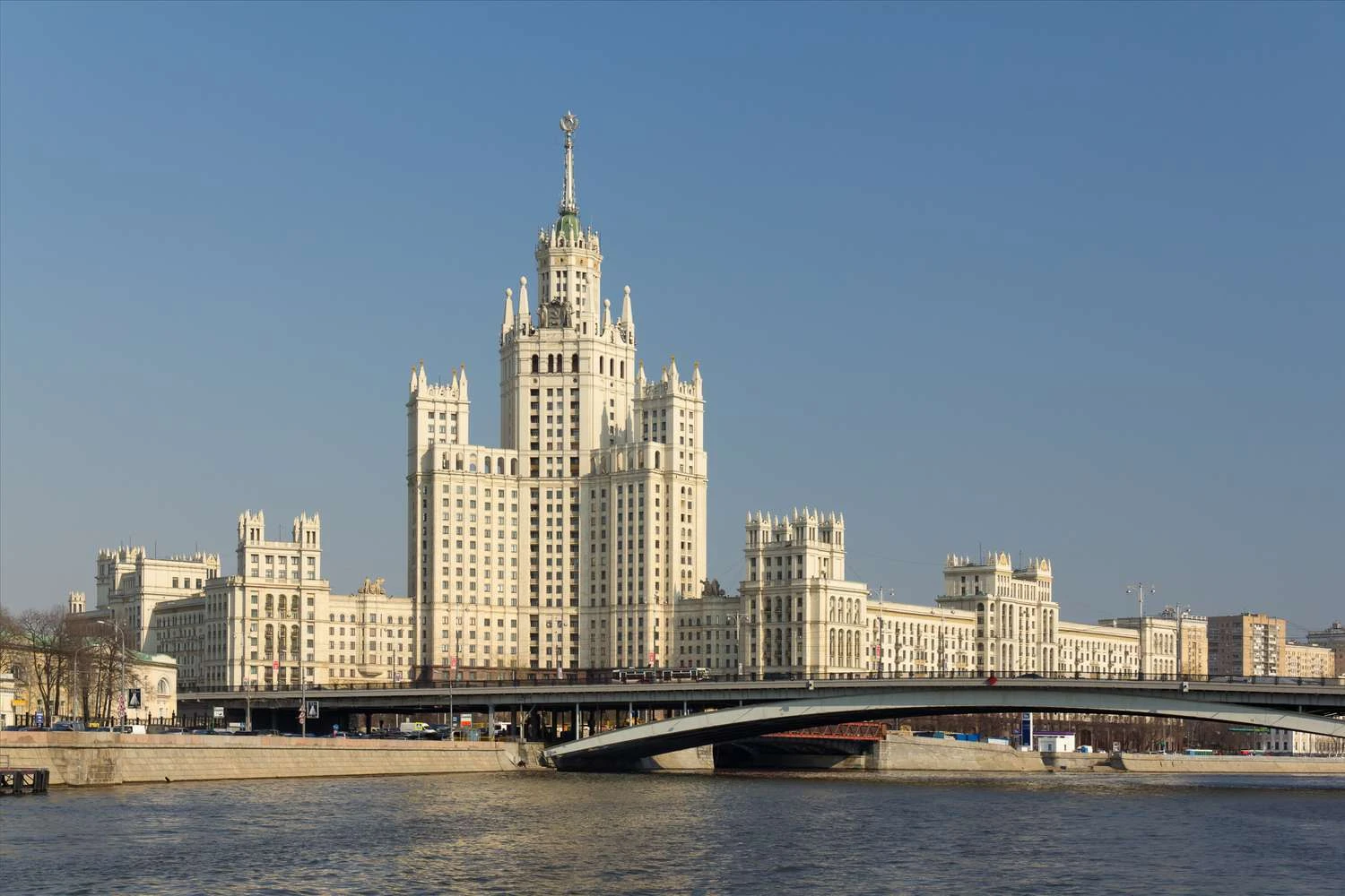 مجموعه ساختمان&zwnj;های چند طبقه سفید روشن پشت یک پل بر روی رودخانه