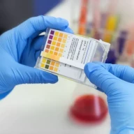 دانشمند از کاغذ لیتموس رنگی در آزمایشگاه شیمی استفاده می‌کند