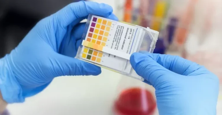 دانشمند از کاغذ لیتموس رنگی در آزمایشگاه شیمی استفاده می‌کند