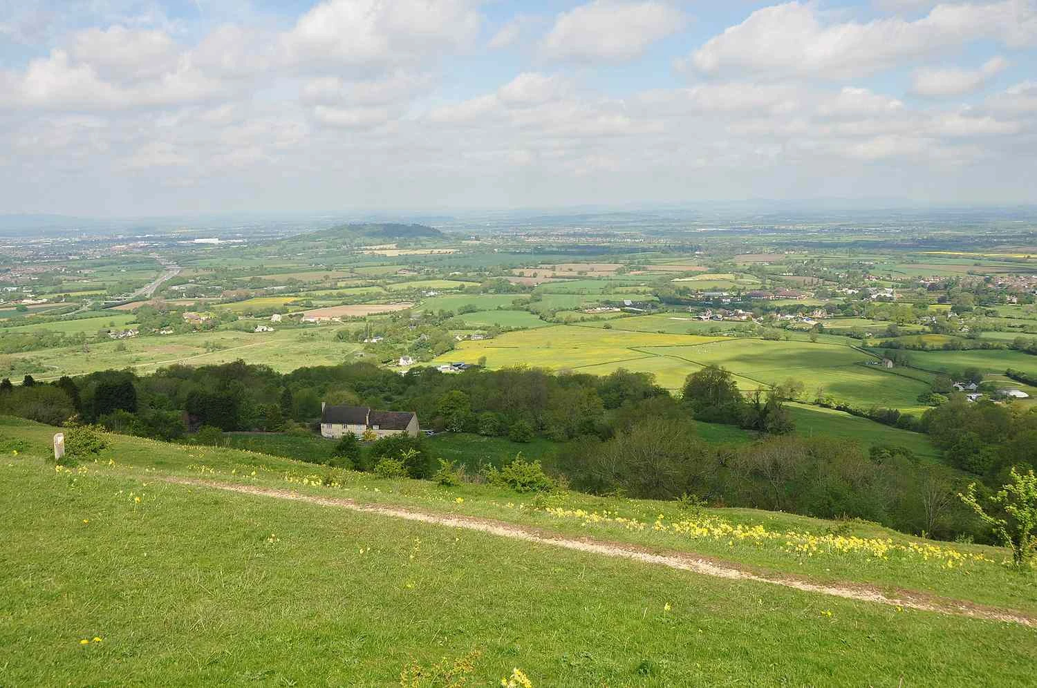 تپه کریکلی در یک روز آفتابی با مزارع و خانه&zwnj;ها در پس&zwnj;زمینه