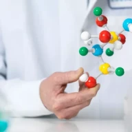 دانشمندی که مدلی از یک ترکیب را در دست دارد