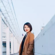 خانم جوانی در حال قدم زدن در بندر، در مقابل منظره شهر هنگ کنگ