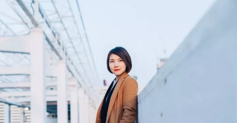 خانم جوانی در حال قدم زدن در بندر، در مقابل منظره شهر هنگ کنگ