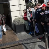 صف مضطرب مصرف‌کنندگانی که منتظر خرید اولین ساعت اپل هستند و مردی خندان که یکی از آنها را خریده است، نمادی از جنبه‌های فرهنگ مصرف‌گرایی هستند.